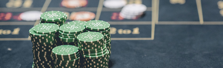 Green chip stacks with different height on roulette table with depth of field